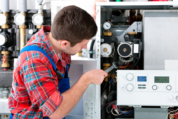 HVAC technician inspecting and repairing boiler controls in Eagle Mountain