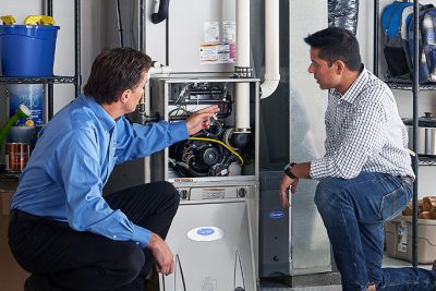 HVAC technician explaining furnace repair and maintenance to a homeowner in Eagle Mountain, UT